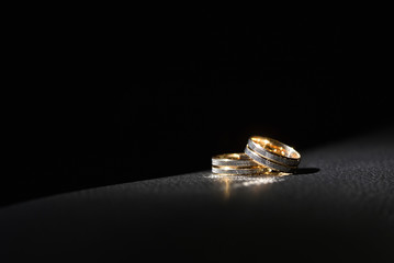 Gold wedding rings on a black background with text space. The concept of a gloomy and unsuccessful...