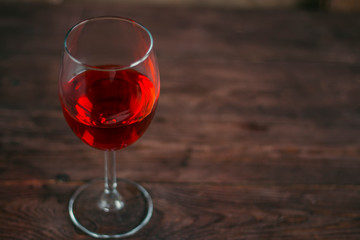 Red wine in a glass goblet on wooden background. Alcoholic drinks.