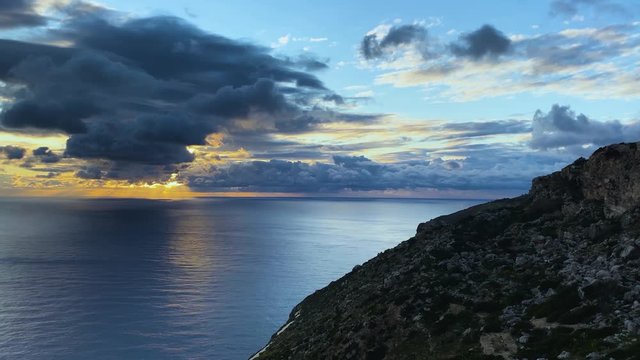 Sunset over the sea timelapse. Golden sun rays shining through the dark stormy clouds.