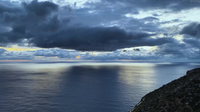 Breathtaking sunset at sea with dramatic sky and beautiful light between dark stormy clouds.