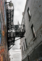 Low angle view of the exterior fire escape from one building into the alleyway between two buildings. cityscape