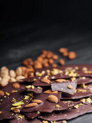   Dark chocolate chips with nuts stacked on a wooden board surface
