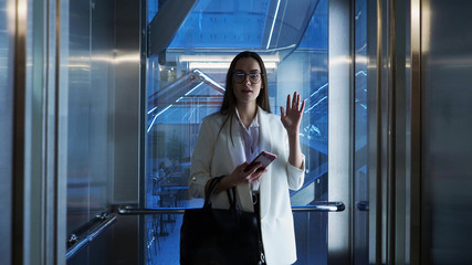 Young business lady in the Elevator in the business center, informal greeting of colleagues.