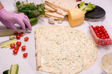 Round pita bread with cheese, cucumber, herbs, mayonnaise. Cooking snacks