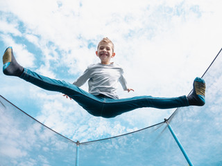 boy jumping on trampoline, open legs