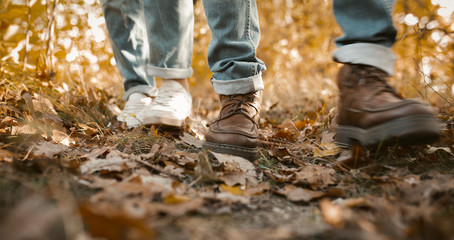 Couple In Jeans Walking Along Autumn Leaves