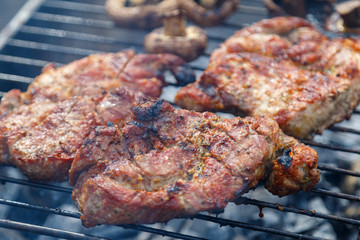 The process of cooking barbecue steaks on an open fire.