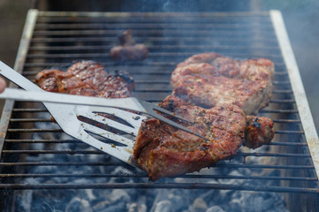 The process of cooking barbecue steaks on an open fire.