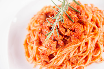 Spaghetti bolognese on a plate decorated with a rosemary twig