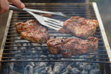 The process of cooking barbecue steaks on an open fire.