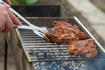 The process of cooking barbecue steaks on an open fire.