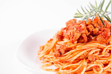 Spaghetti bolognese on a plate decorated with a rosemary twig