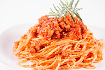 Spaghetti bolognese on a plate decorated with a rosemary twig
