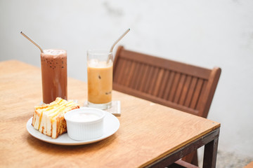 Set of breakfast consist of egg bread (sandwich) with egg sauce and ice cocoa and coffee (latte) on table - homemade food concept.