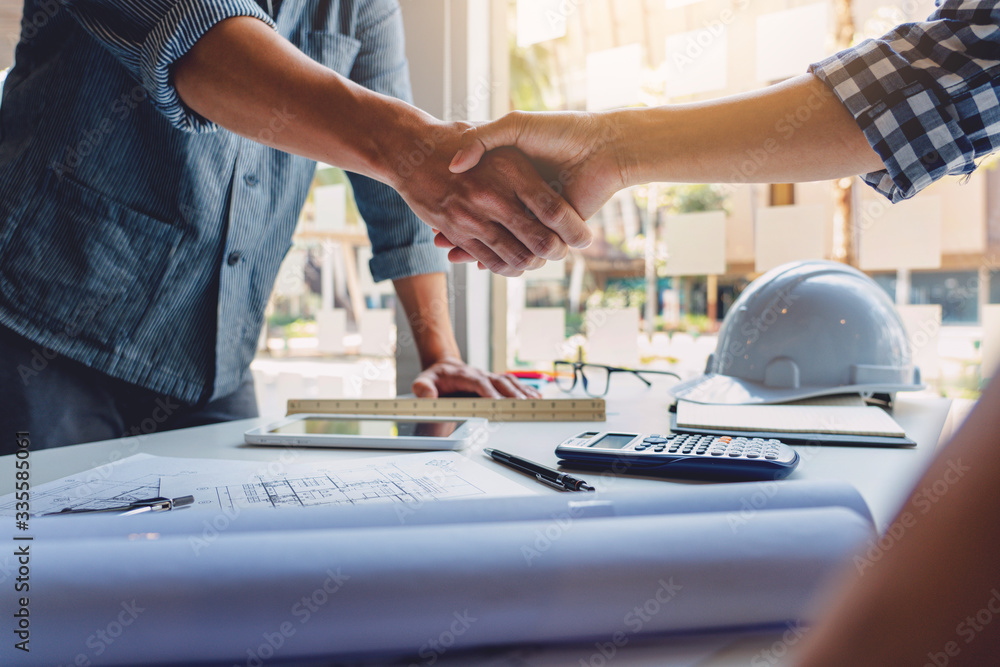Poster architect and engineer construction workers shaking hands while working for teamwork and cooperation