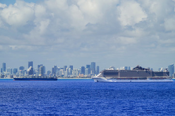 MSC Seaside huge modern cruiseship or cruise ship liner and tanker at sea with skyline of Miami or...