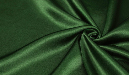 Smooth elegant green silk or satin luxury cloth texture can be used as abstract background. Crumpled fabric Twisted at the side.