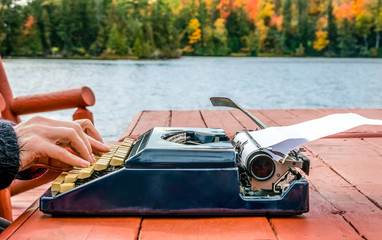 Work from anywhere - working on typewriter beneath the autumn sky while on a deck near the water's edge. concept - background