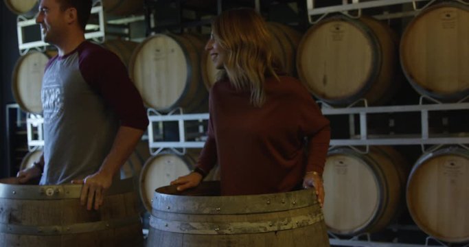 Young Couple In 20s Crushing Grapes With Their Feet In Vineyard Wine Barrels