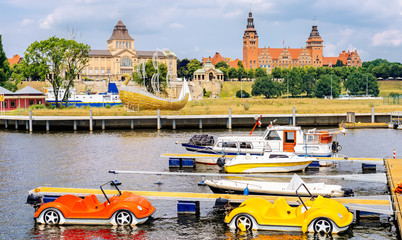 Pedalos and boats docked on Rampart of Brave embankment of Odra River. National Museum, Regional Authority and Passport Office in background, Szczecin - obrazy, fototapety, plakaty