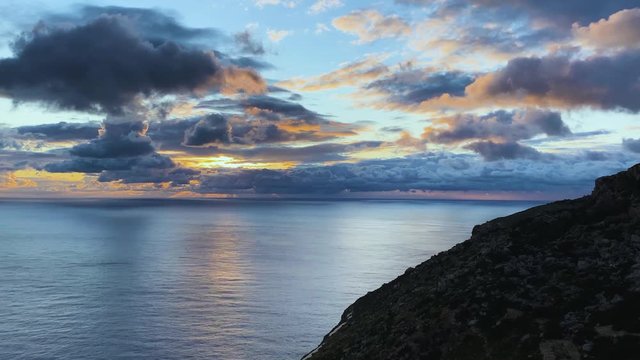 Beautiful golden hour sunset at sea with dramatic sky and sun rays between the clouds