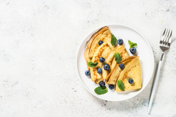Crepes with blueberries at white table.