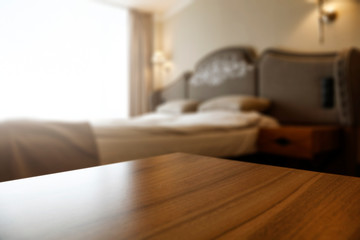 wooden desk of free space and blurred home interior with bed 