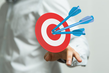 hand holding a target with darts hitting the center over white background. Concept of .
