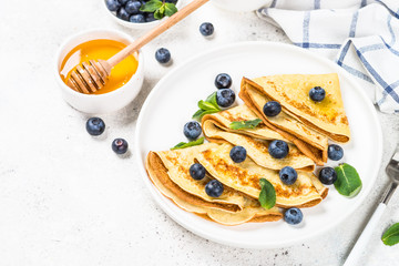 Crepes with blueberries at white table.