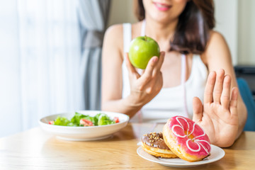 Obraz na płótnie Canvas Asian young woman refuse junk food while choose to eat healthy salad and fruit for her healthy. Girl take care of herself by having high nutrition food every day. Good food for healthy Dieting concept