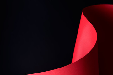 Abstract - waved paper crafting - rolled red paper on a black background. Simple, isolated object with text space perfect for illustrating various concepts and ideas. Selective focus (shallow DOF).