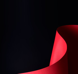 Abstract - waved paper crafting - rolled red paper on a black background. Simple, isolated object with text space perfect for illustrating various concepts and ideas. Selective focus (shallow DOF).