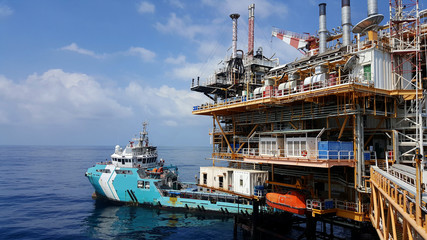 Supply boat (crew boat)  transfer worker and cargo by personnel basket from platform to supply boat of oil and gas industry.