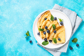 Crepes with blueberries at blue table.
