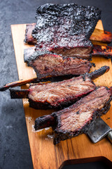 Barbecue burnt chuck beef ribs marinated and sliced as closeup on a modern design wooden board