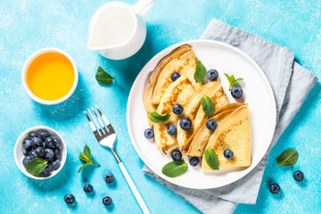 Crepes with blueberries at blue table.