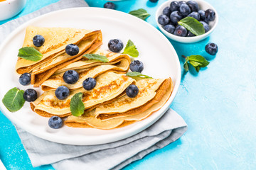Crepes with blueberries at blue table.