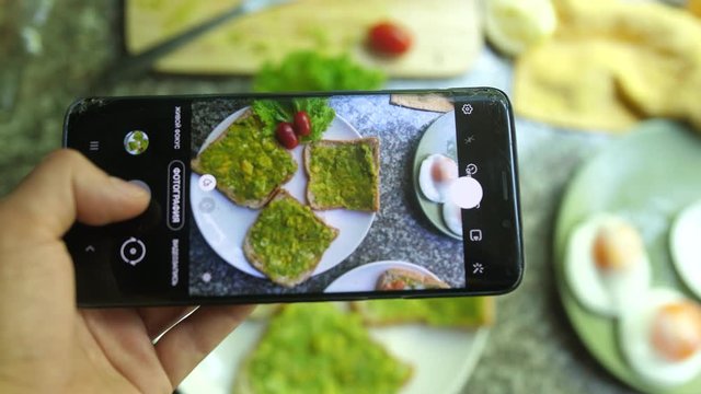 Taking Photos Of Healthy Avocado Bruschetta. Mobile Food Photography Concept.