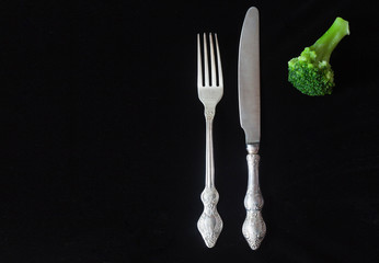 fork knife and broccoli on a black background