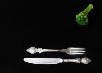 fork knife and broccoli on a black background
