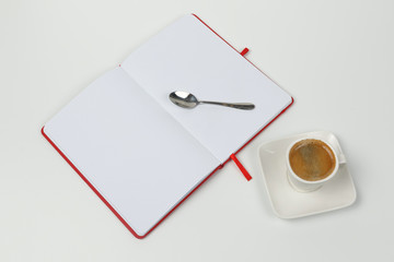 Cup of coffee, notebook and spoon on a white background.