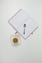 Cup of coffee, notebook and spoon on a white background.