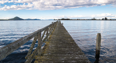 Naklejka premium Old wooden wharf centered shot during sunset. Location is Tokaanu Wharf locate in Taupo region of North Island, New Zealand.