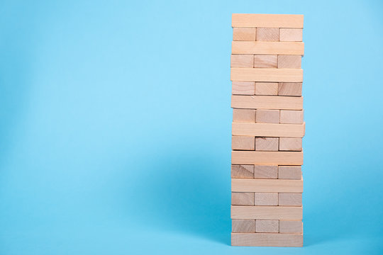 The tower is made of wooden blocks. Jenga close-up. On a blue background