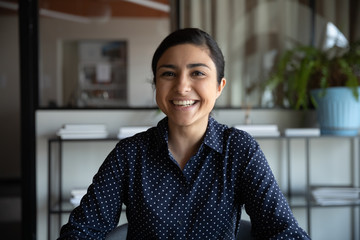 Excited young indian ethnicity woman looking at camera, holding funny conversation with colleagues...