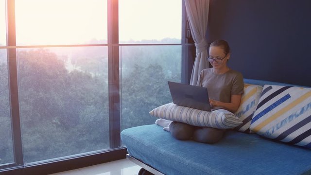 Young woman working from home office. Freelancer using laptop, phone and the Internet. Workplace in living room on windowsill. Quarantine time. COVID - 19 concept.
