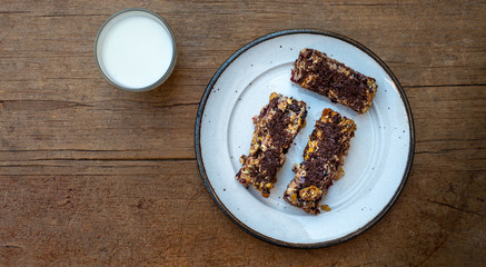 home made healthy cereal bars.in kitchen with glass of milk  honey pot ,& drizzler,