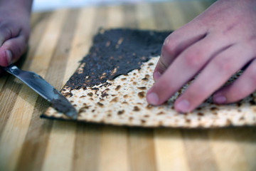 A child's hands are spread chocolate on matzah. Matzah - a traditional Jewish food for Passover.