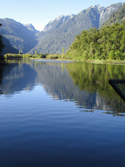 Fototapeta na wymiar Mountains and trees reflected in still lake 