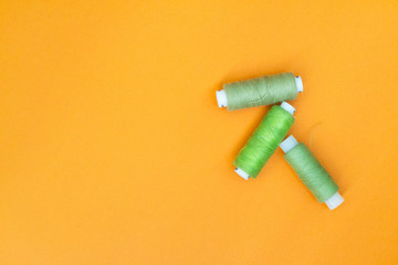Green spool of thread on a yellow background. The concept of needlework, sewing.